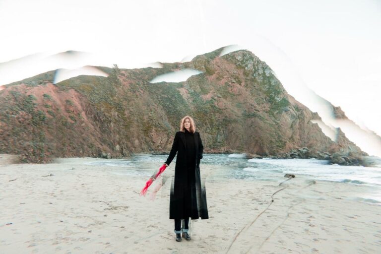 Beth Orton posing alone on a beach for a press photo