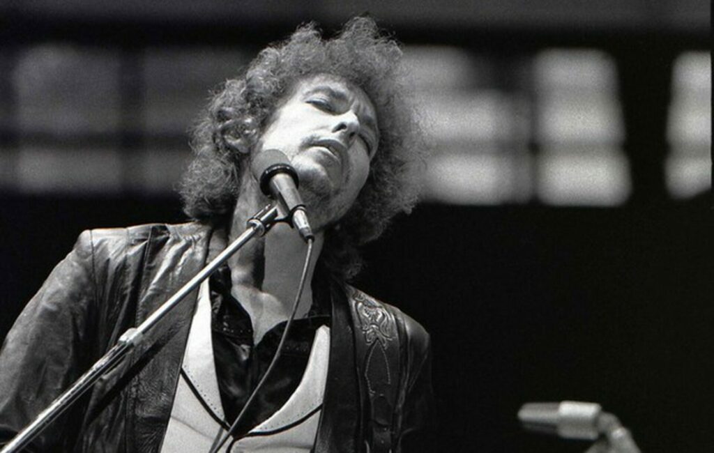 Bob Dylan performs live in a black and white stage shot