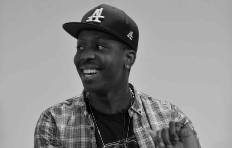 Jamal Edwards wears a hat and checkered shirt in a black and white image