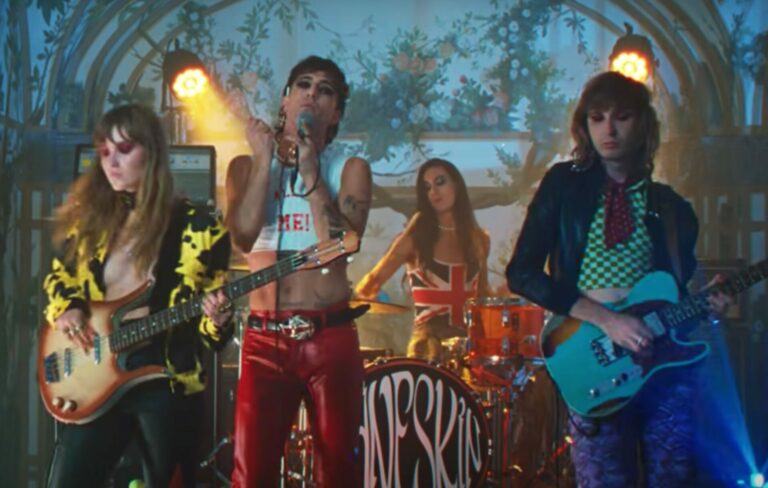 Maneskin stand together in a band formation wearing eccentric clothes in the 'MAMMAMIA' music video