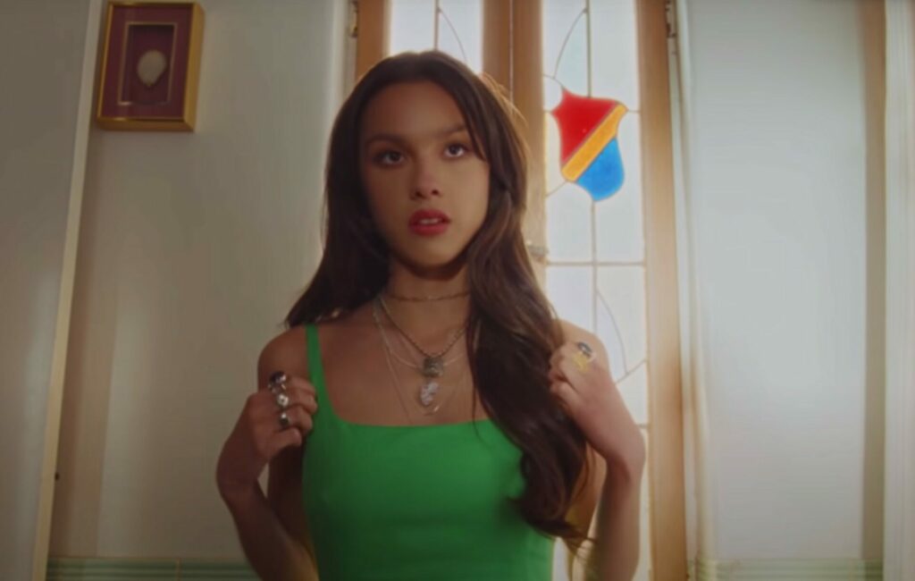 Olivia Rodrigo wears a green vest in the music video for deja vu