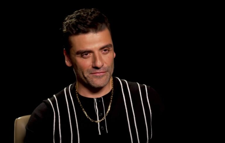 Oscar Isaac wears a black shirt with white stripes in a junket interview
