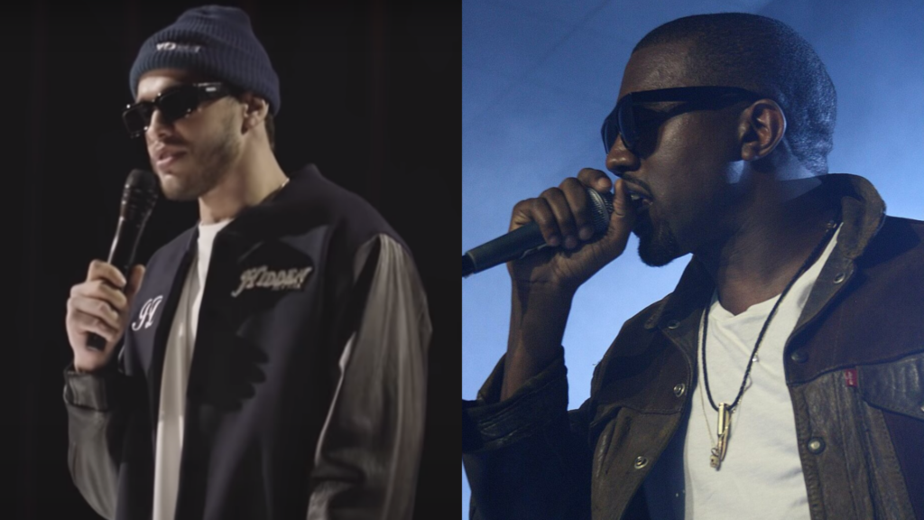 Pete Davidson wears a hat and sunglasses during a set next to a picture of Kanye West performing