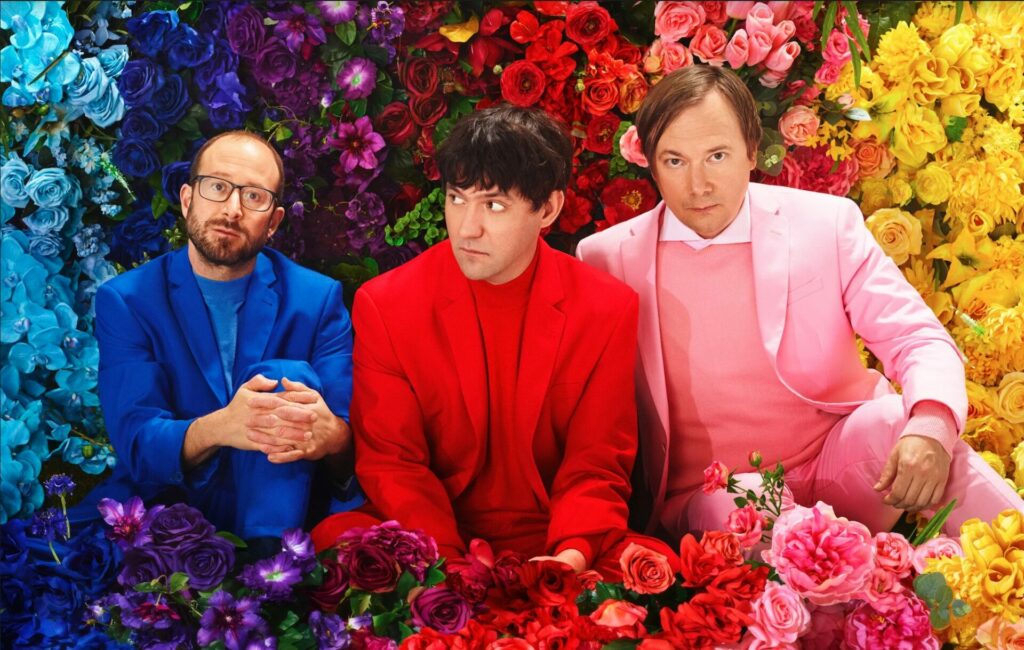 The three members of Bright Eyes pose in a colourful flower bed