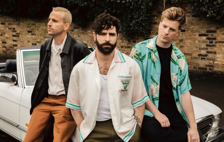Foals pose in a press shot, sitting on a car