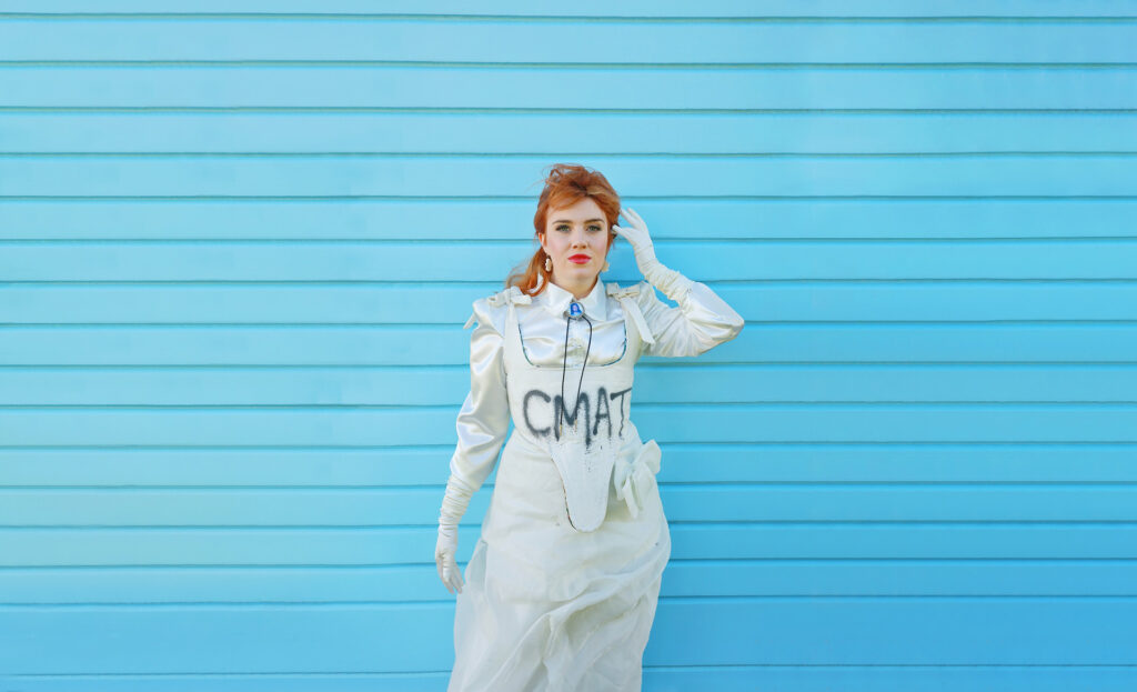 CMAT photographed for a publicity image, with the word 'CMAT' spraypainted on her dress