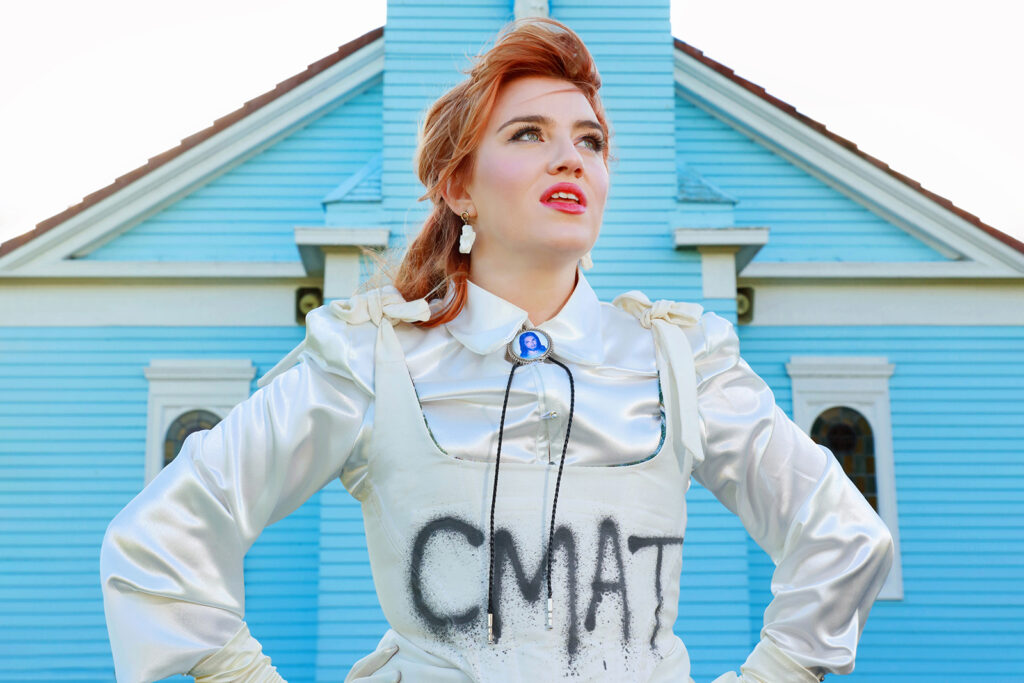 CMAT photographed for a publicity image outside a blue building