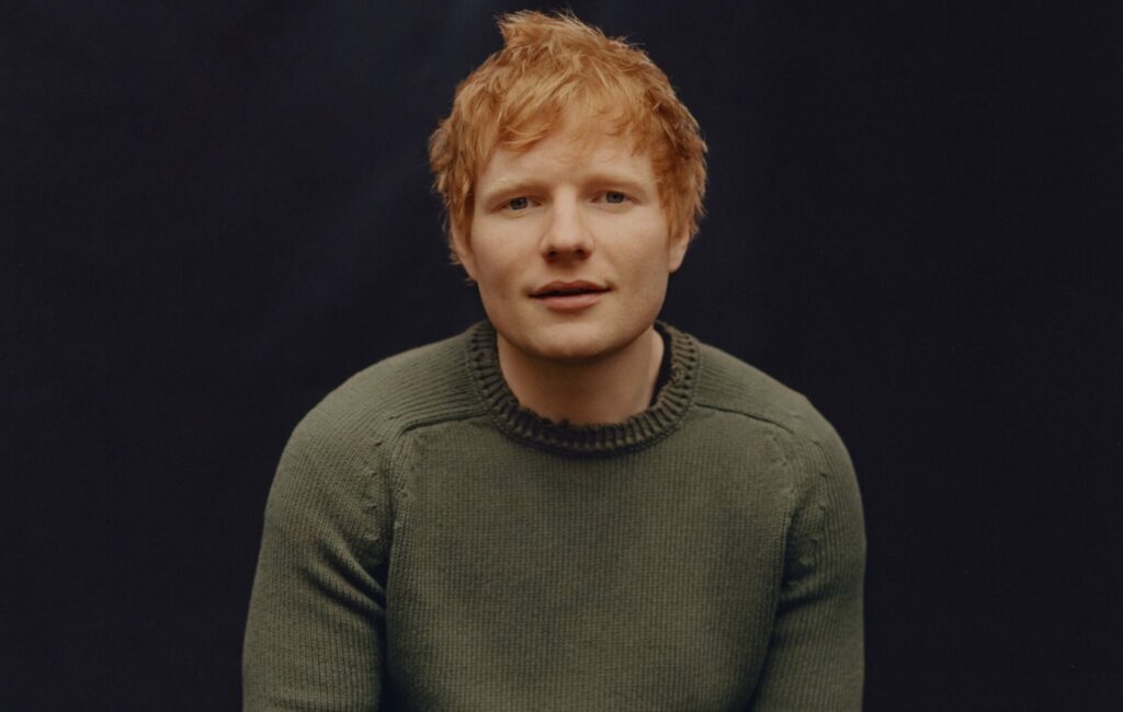 Ed Sheeran wears a grey woolly jumper against a black background