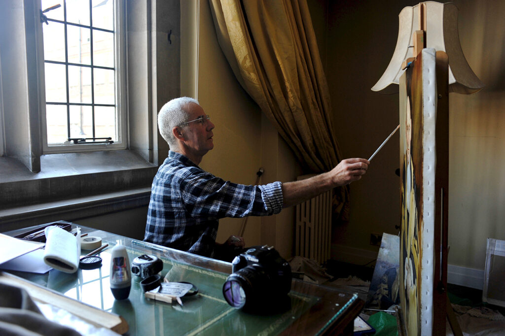 A photograph of artist Keith Breeden painting in his studio