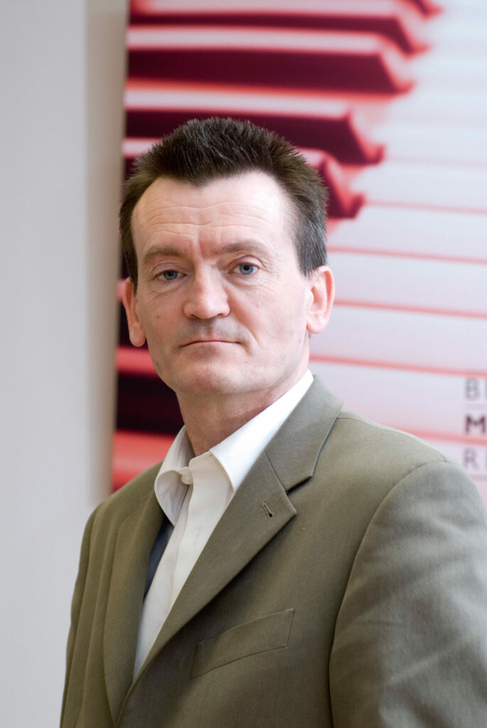 Feargal Sharkey wears a grey suit and white shirt in a headshot