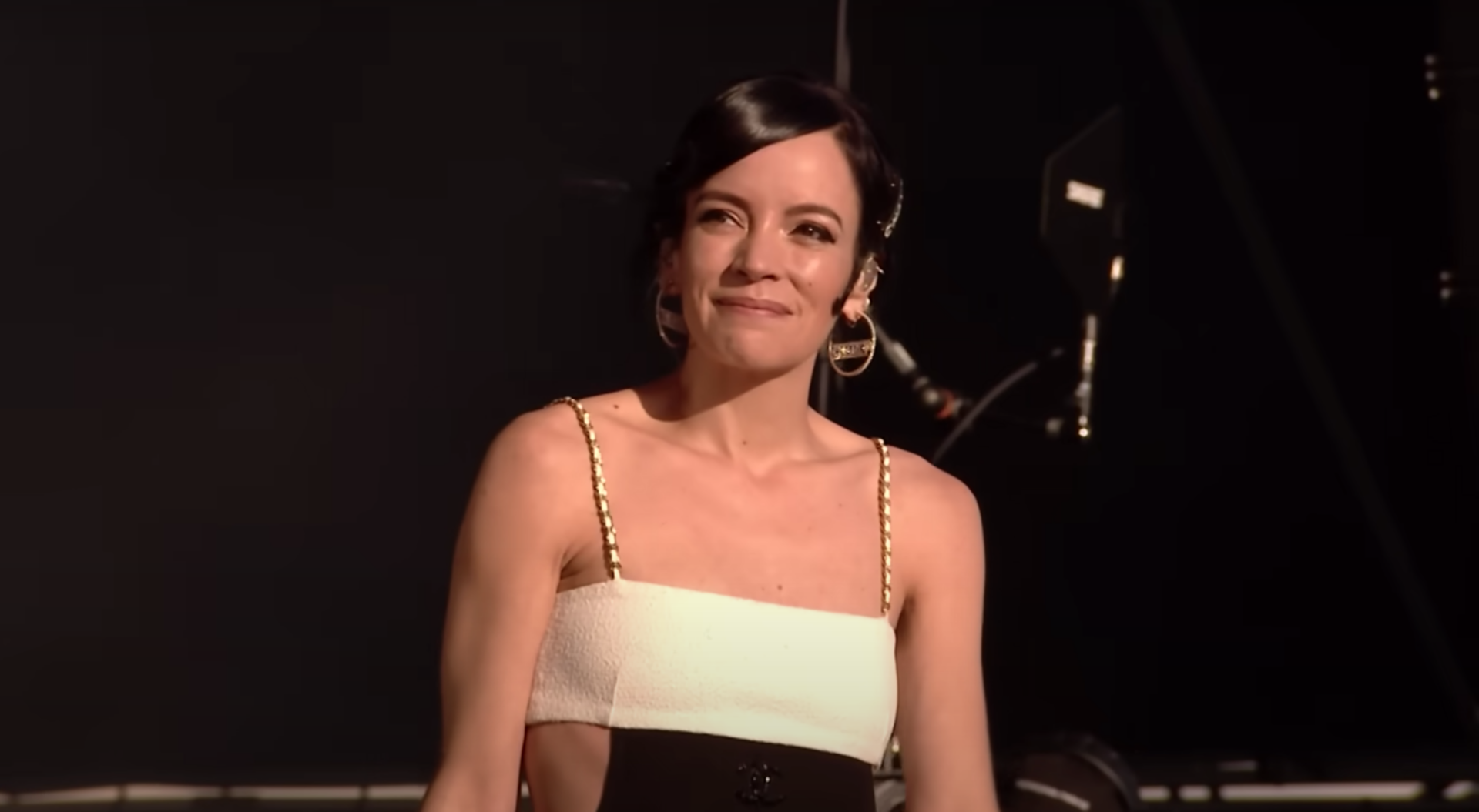 Lily Allen wears a strappy white and black playsuit on stage at Glastonbury