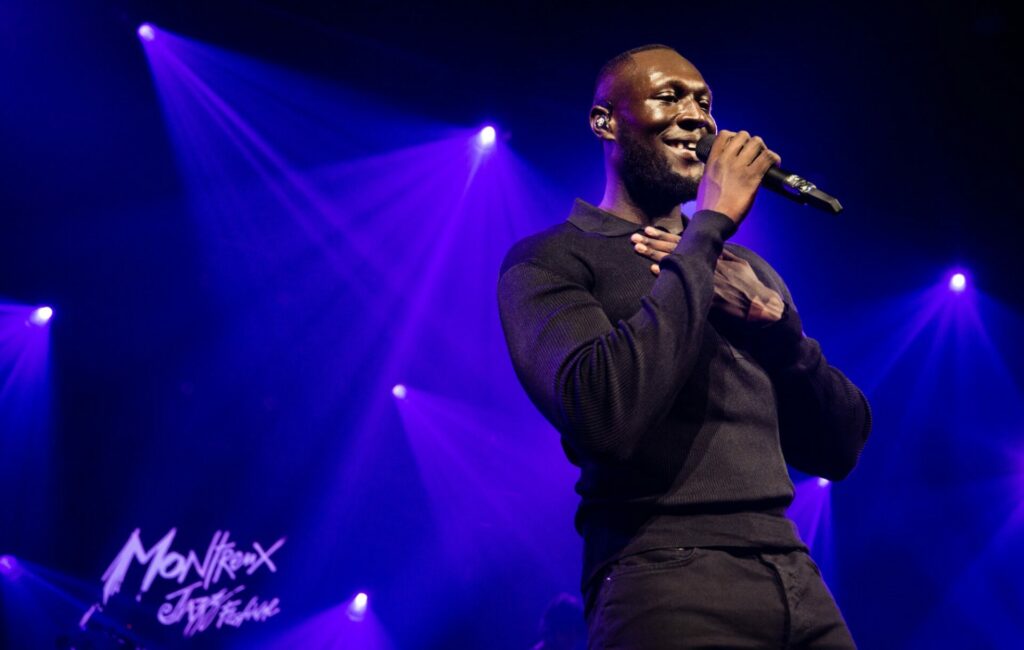 Stormzy wears all black and holds a microphone during a performance at the Montreux Jazz Festival