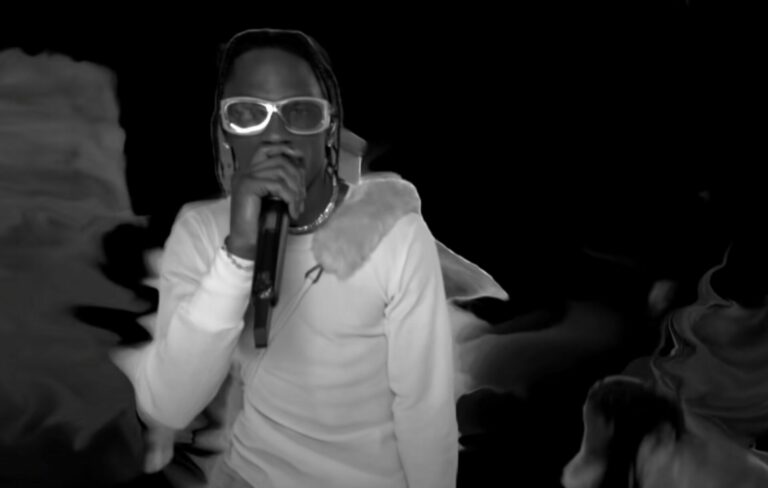 Travis Scott wears a white shirt and glasses performing live at the Billboard Music Awards