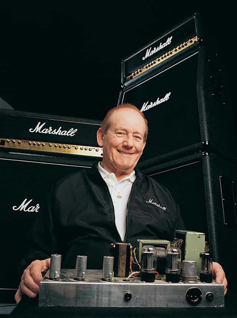 Jim Marshall, founder of Marshall Amplification, photographed in front of a Marshall Stack