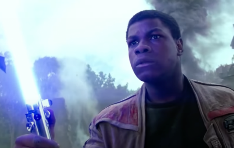 John Boyega holds a blue lightsaber in ‘Star Wars: The Force Awakens‘