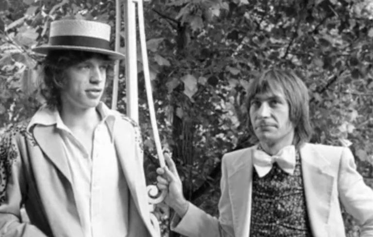 Mick Jagger and Charlie Watts wear suits and a bowtie in an old black and white picture