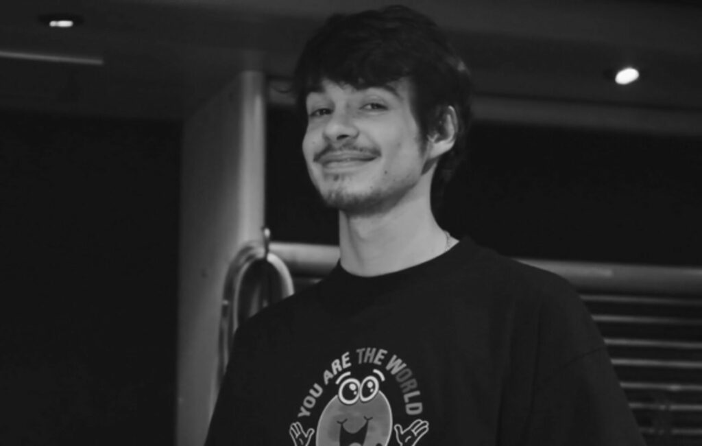 Rex Orange County smiles at the camera in a black and white headshot