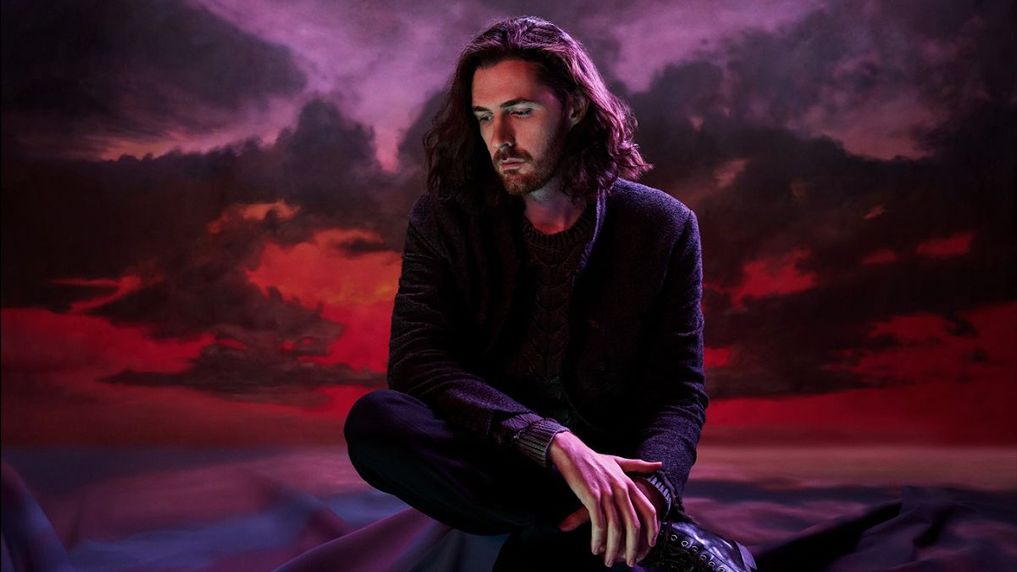 Hozier poses with a purple sky behind him