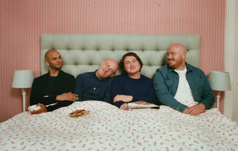Members of the band Bombay Bicycle Club sit up in a bed