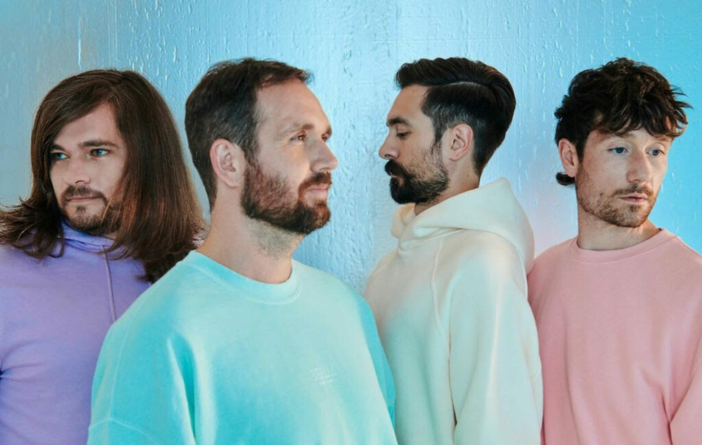 Members of Bastille pose in pastel-coloured jumpers