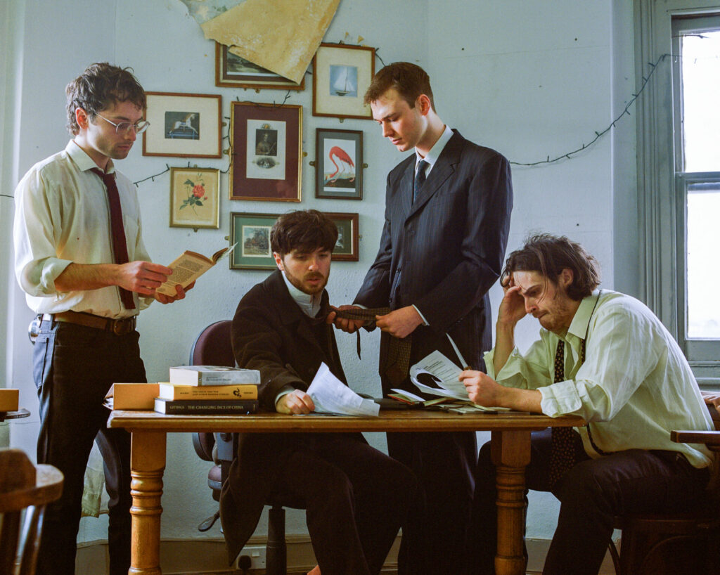 A group of men sit around the table looking at books