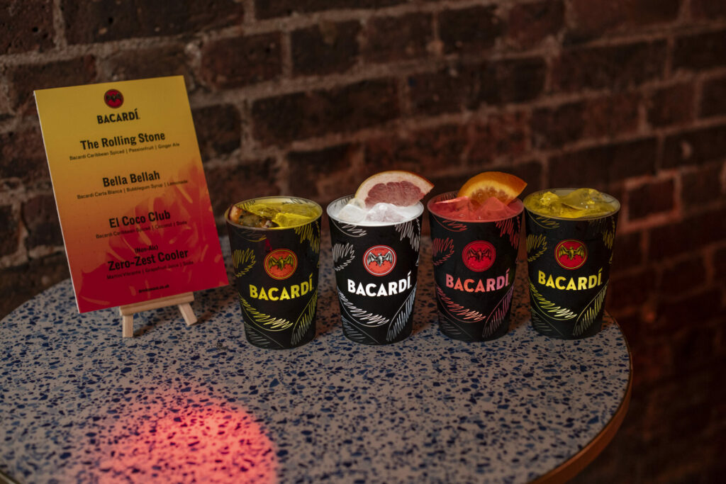 A row of  BACARDÍ cocktails stands on a table next to a cocktail menu