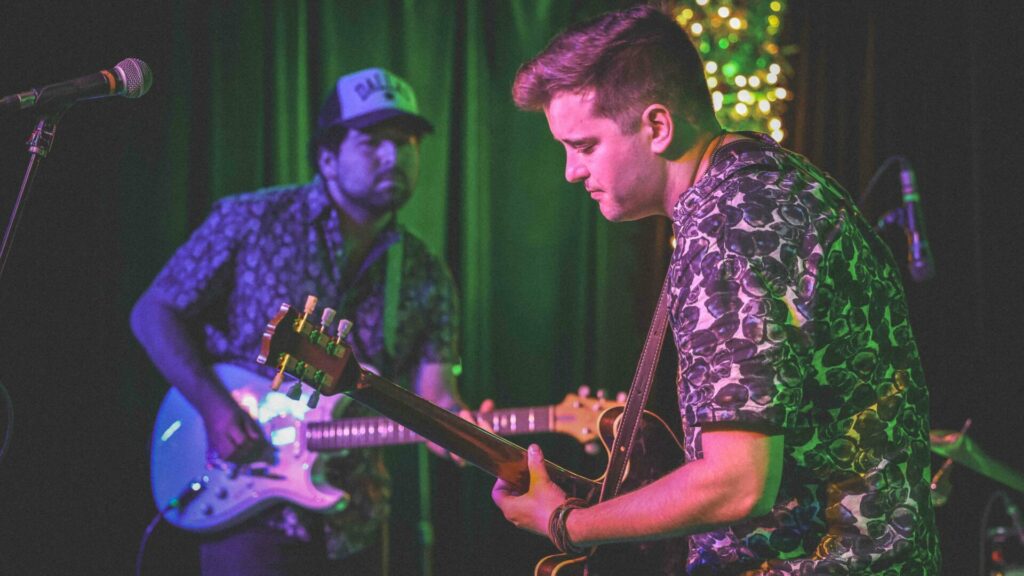 Two men perform in a band onstage