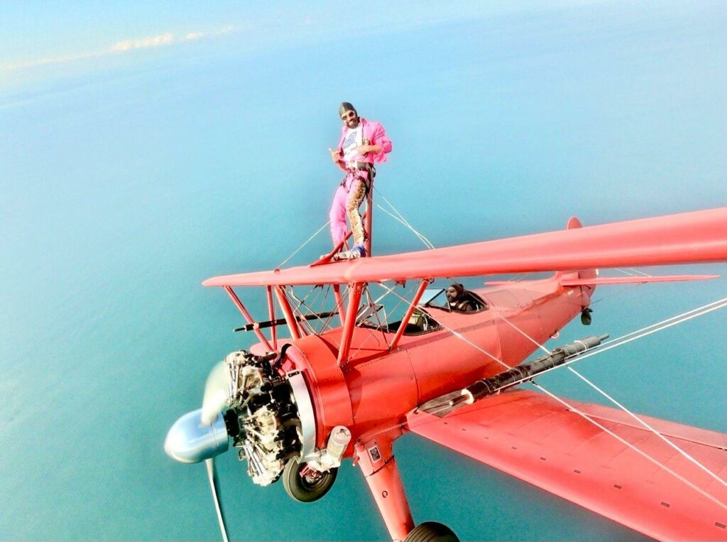 A man wing walking on a red plane