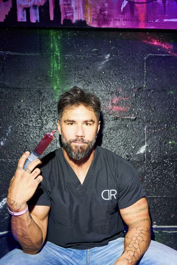 A man in a black shirt holds a red syringe