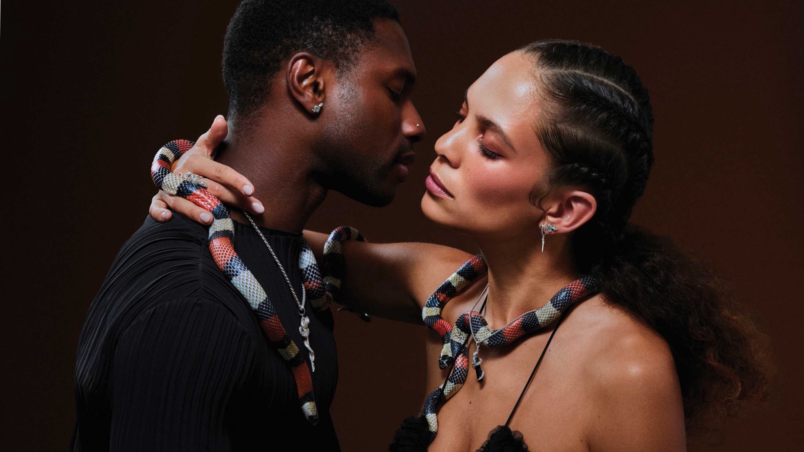 A black couple passionately going in for a kiss with snakes around their necks adorned in Thomas Sabo Rebel Snake collection jewellery