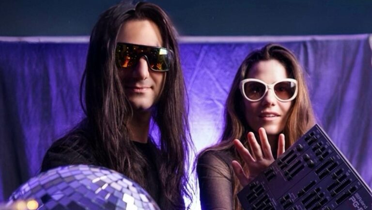 Two purple wearing sunglasses against a purple backdrop