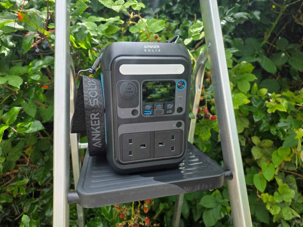 An Anker c300 sitting on a ladder with a bush in the background