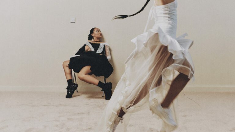 Musician Griff wearing black watches a dancer wearing white jump.