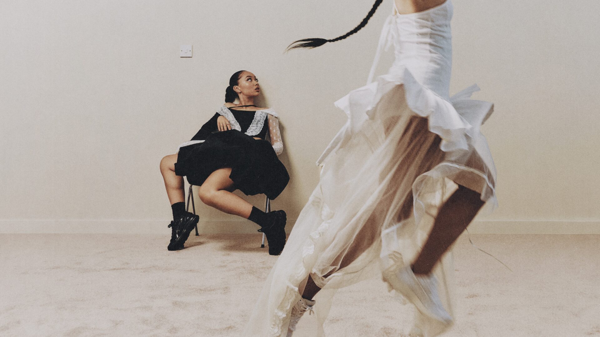 Musician Griff wearing black watches a dancer wearing white jump.