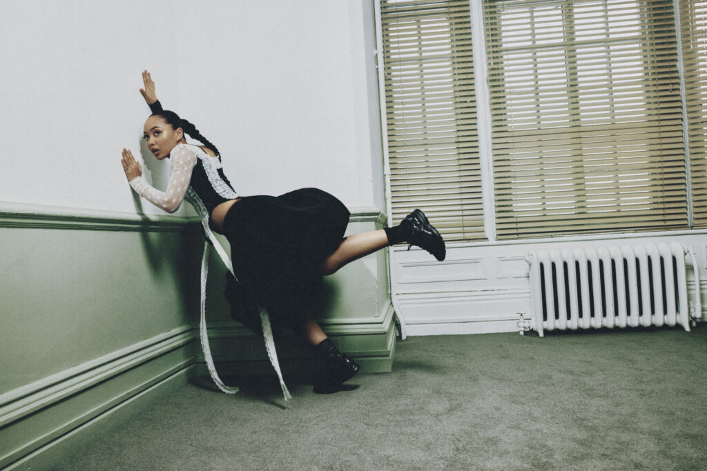 Musician Griff models the ASICS SportStyle JOG 100S trainers in black and white.
