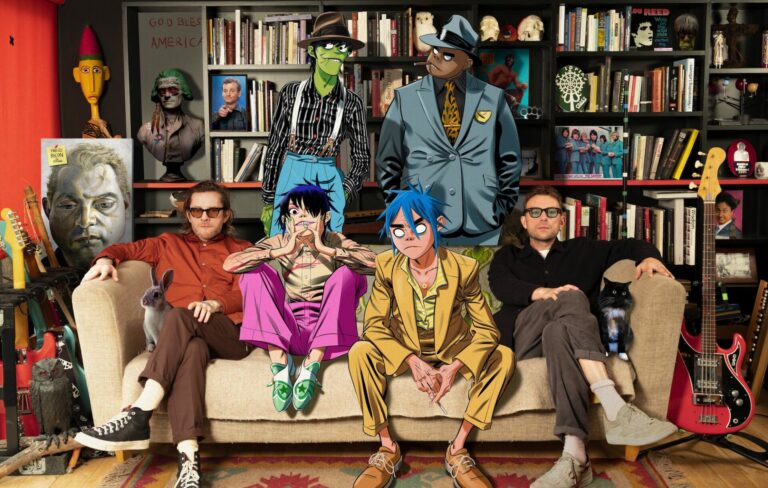 The cartoon members of Gorillaz and their real-life creators pose on a sofa