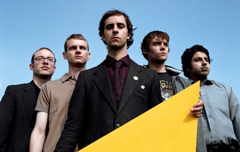 The members of Maximo Park looking down at the camera in front of a blue sky