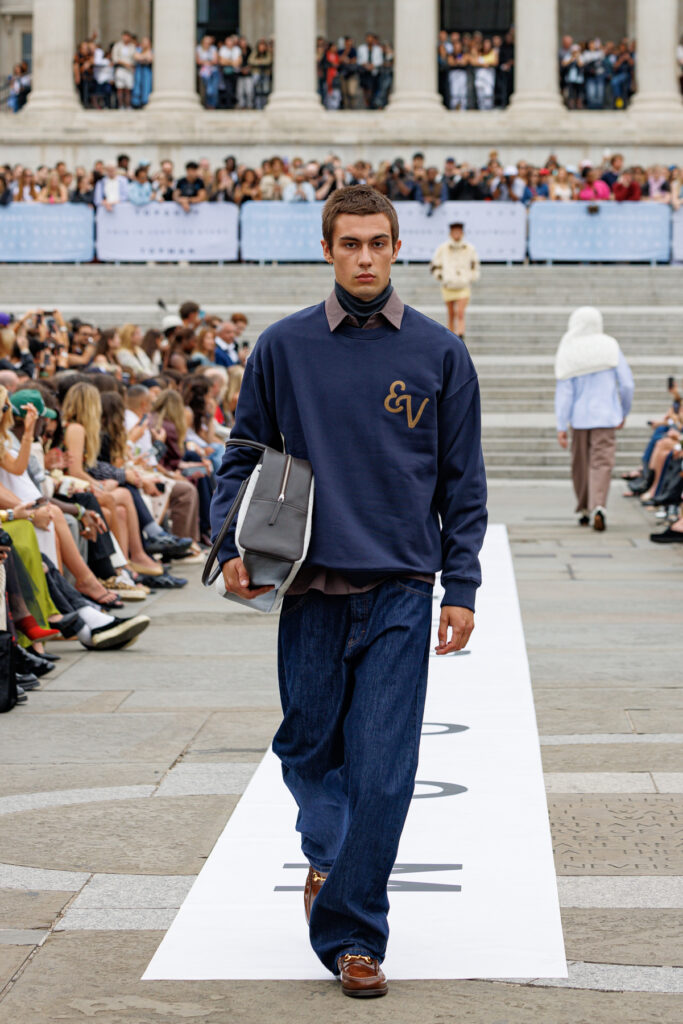 A model wearing a navy, collegiate-inspired crew neck and blue jeans walks the Topman autumn/winter 2025 show in Trafalgar Square.