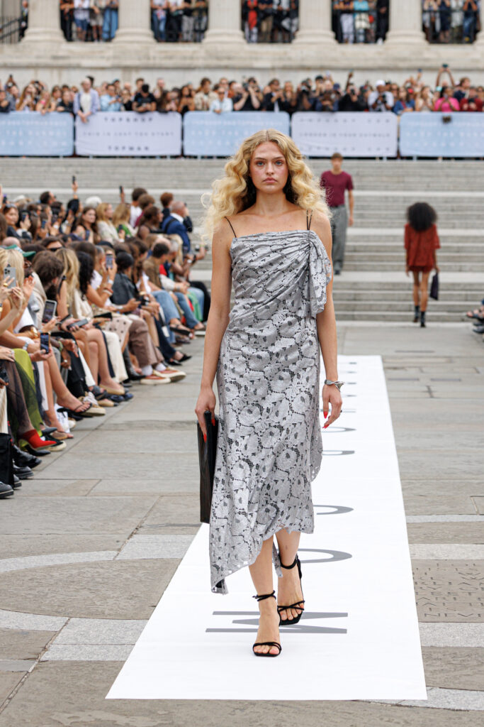 A model wearing a scrappy silver dress walks the Topshop autumn/winter 2025 show in Trafalgar Square.
