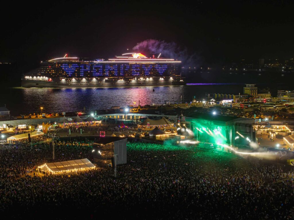 Nightime view of Victorious Festival with a cruise ship in the background