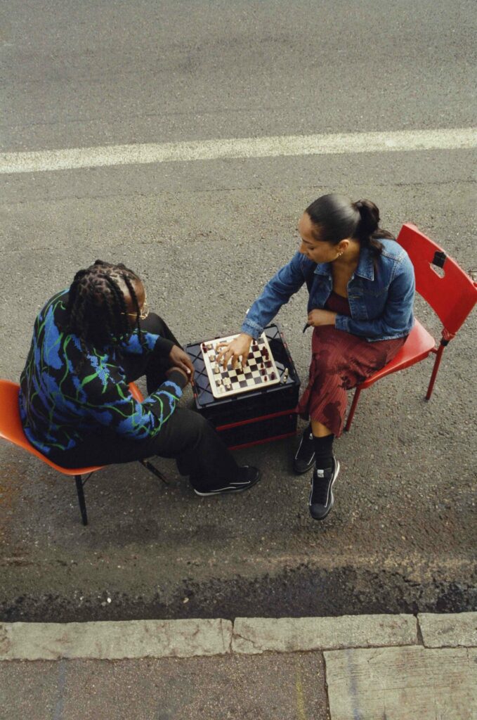 A lifestyle image of The Ahluwalia Puma Suede trainers on two models playing chess in the street. 