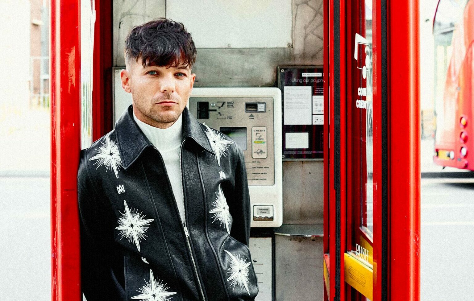 Louis Tomlinson poses in a red phone box