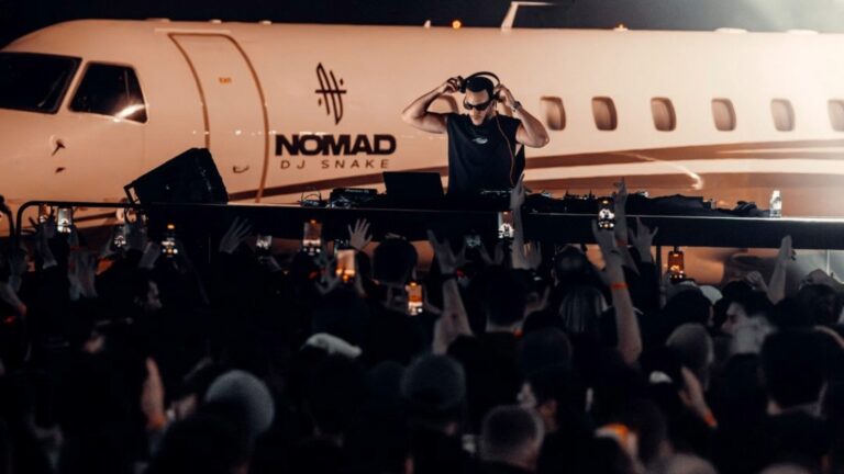 DJ Snake performing in front of a jet in an airport hangar
