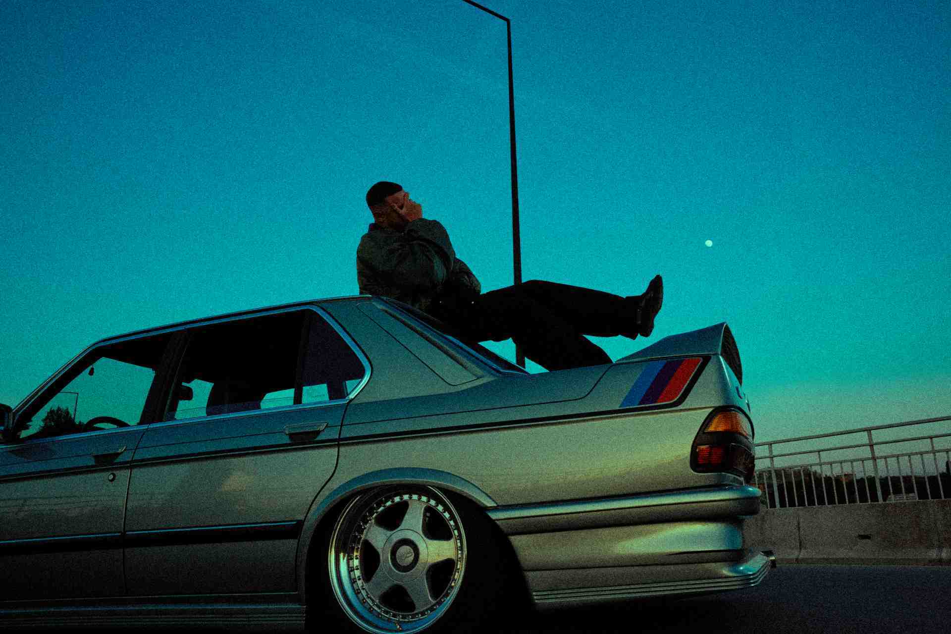 A man poses on a car for DJ Snake's Nomad cover
