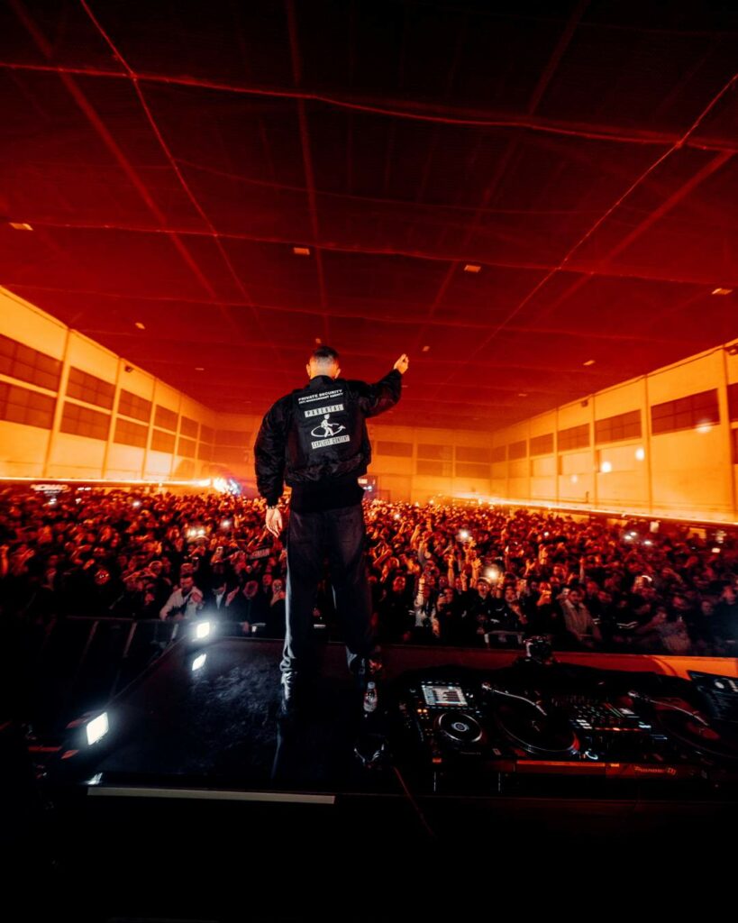 DJ Snake performs to a large crowd inside an airport hangar