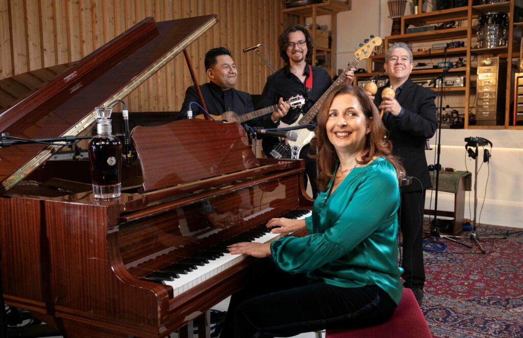 A woman pianist and a a  trio of male musicians sitting by a piano